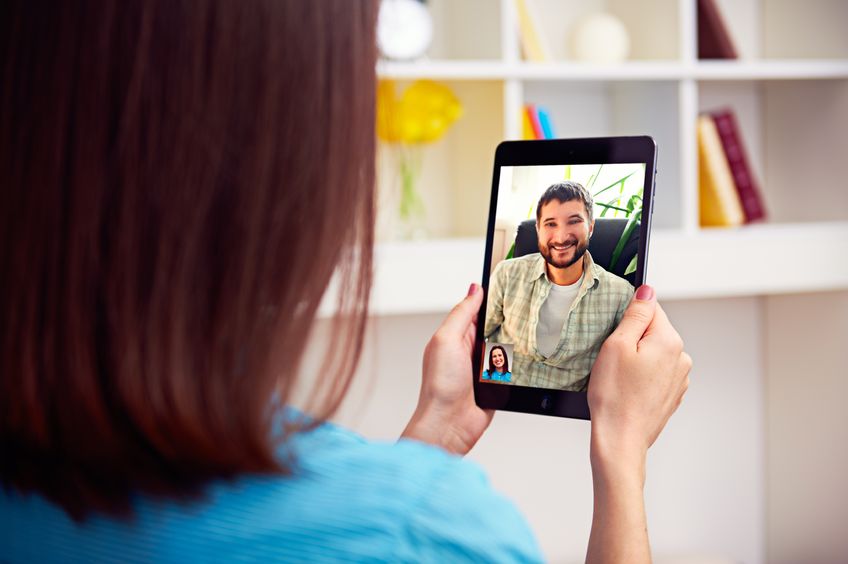 a woman holding an ipad and video calling her partner