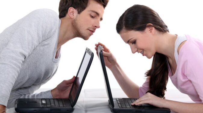 couple using laptops on bed