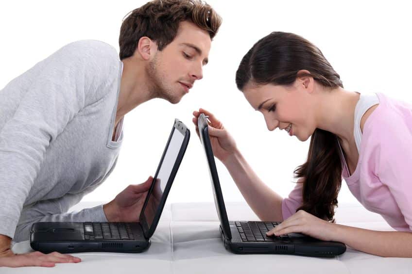 couple using laptops on bed