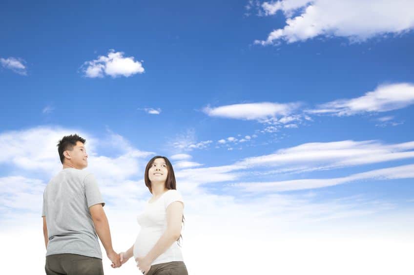 pregnant woman holding her husband and looking at the sky