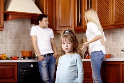 A child with her parents arguing at the back