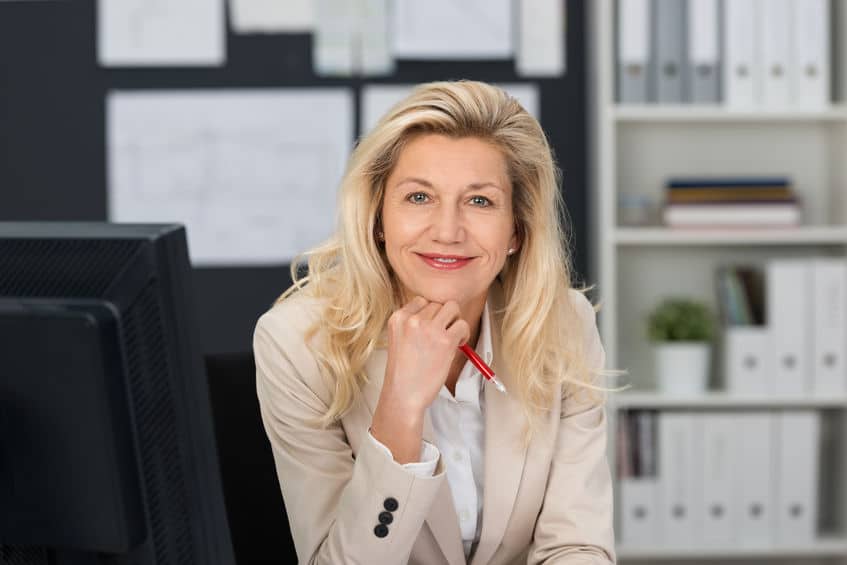 a smiling mature woman with red pen on her hand