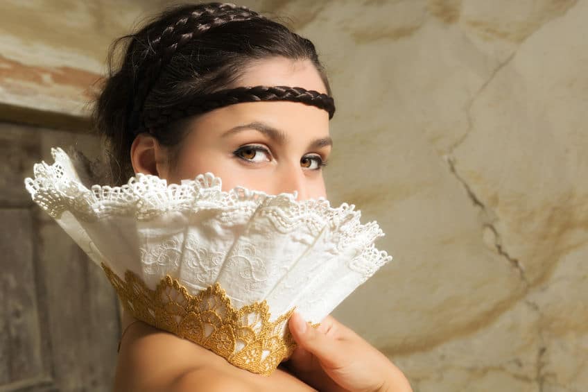 beautiful woman covering half of her face with a white fan like lace