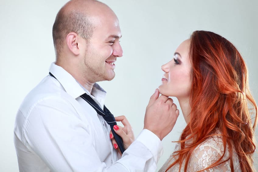 man holding his woman's chin, woman holding her man's tie