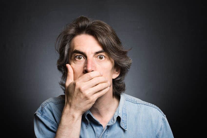 a surprised man hiding his mouth by his hand