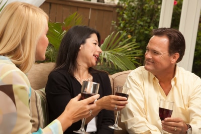 2 women and 1 man drinking wine, on the couch