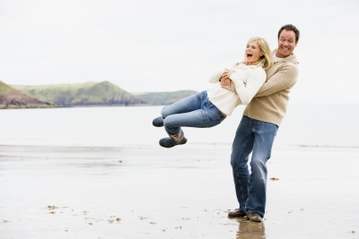 man happily carrying his woman at the beach