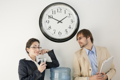 work colleagues talking under clock, drinking water