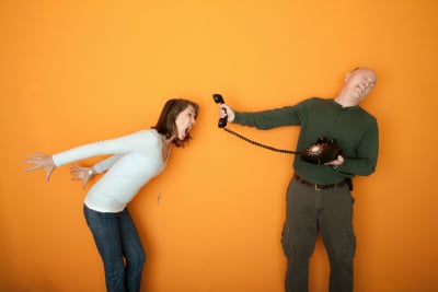 Man holds telephone while angry woman shouts into it