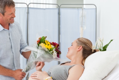 husband gives flowers to his wife at the hospital