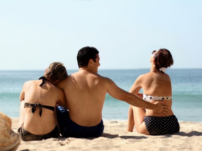 man in between two woman, one holding close to his arms