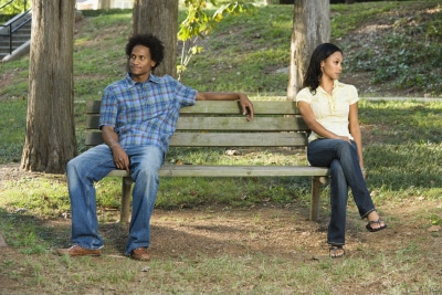 couple sitting far from each other on a bench