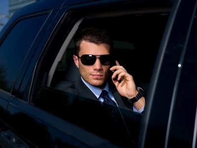 a business man on his phone riding a black car