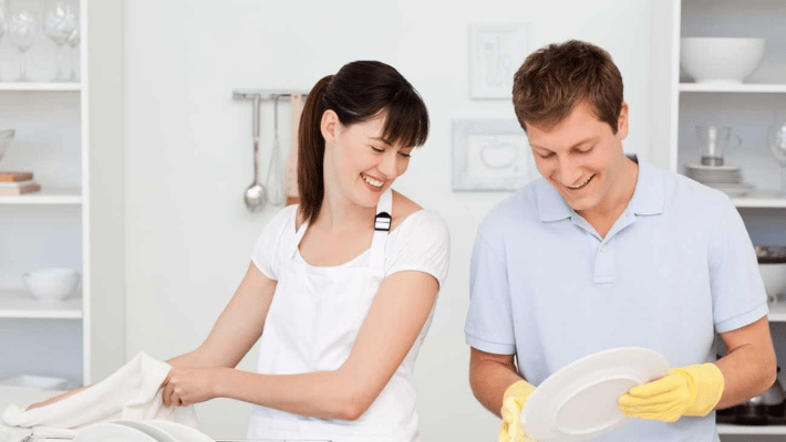 Lovers washing dishes together in their kitchen