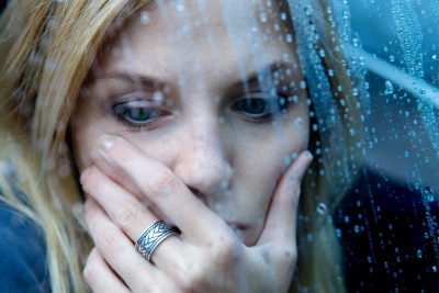 a woman holding her face sitting near the window