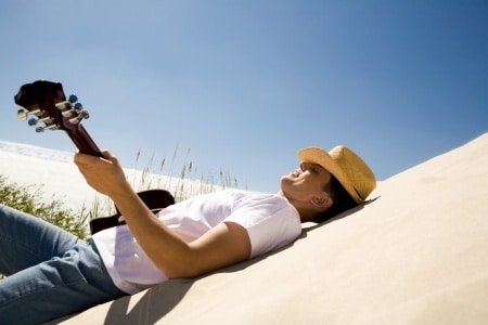 a man playing the guitar under the heat of the sun