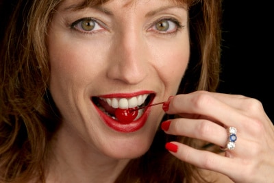 a woman with a cherry inside her mouth