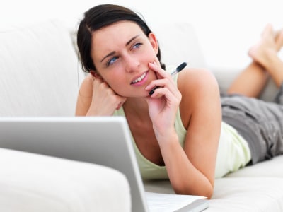 woman lying on a sofa while thinking about different online dating advice