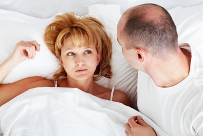 a couple on white bed staring at each other