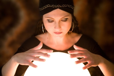Pretty gypsy woman with her hands above her crystal ball predicting the future