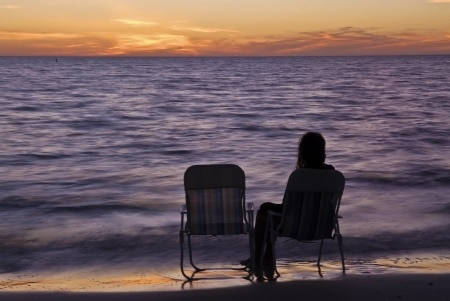 young woman sitting near the beach watching the sunset