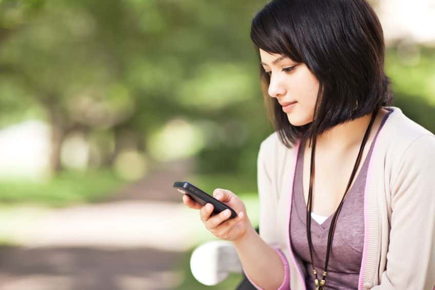 short haired woman using mobile phone at the park