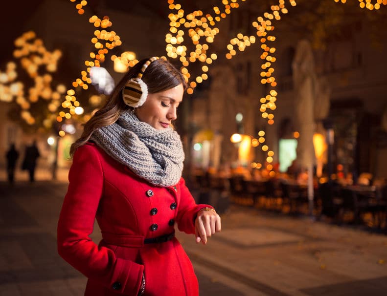 Lady wearing red sweater watching her watch while waiting for his boyfriend