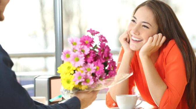 guy giving flowers to a pretty smiling girl