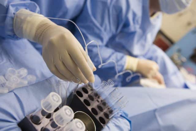 Nurse assisting with egg retrieval procedure in theatre