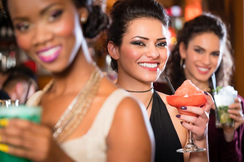 multicultural group of women after work drinking cocktails in bar