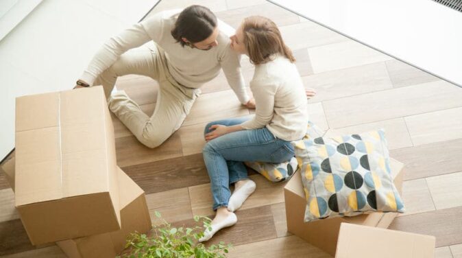 Couple sitting on floor with boxes, moving day, top view