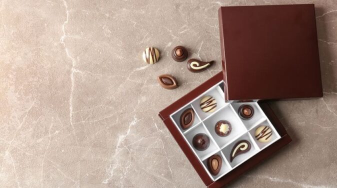 Box with different tasty chocolate candies on table, top view