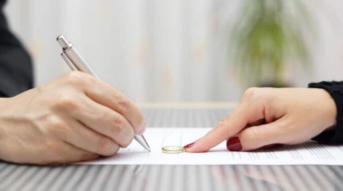 husband signing divorce agreement and woman push away weeding ring