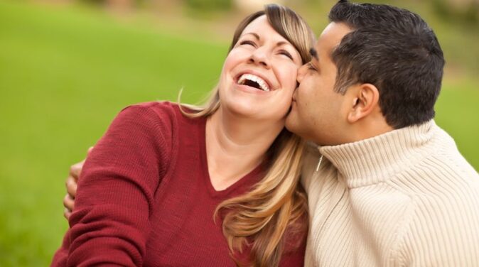 happy woman wearing red sleeve kissed by her husband