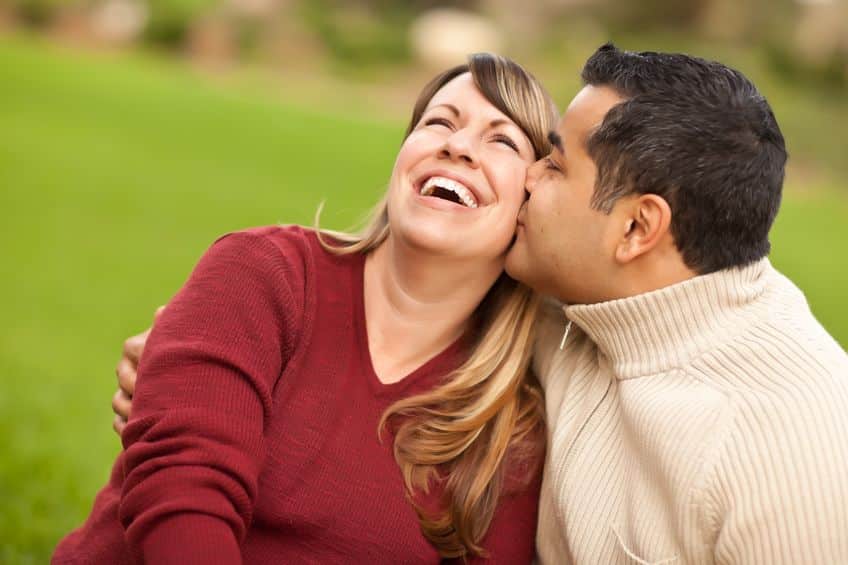 happy woman wearing red sleeve kissed by her husband