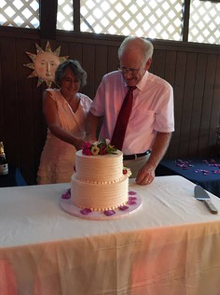 Love U success story of a happy couple smiling while slicing a cake.