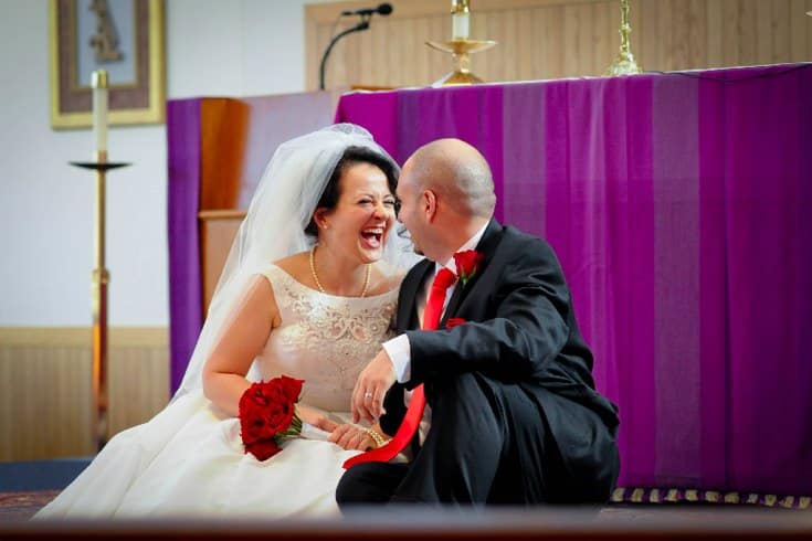 newly-wed couple happily sitting in front of church altar