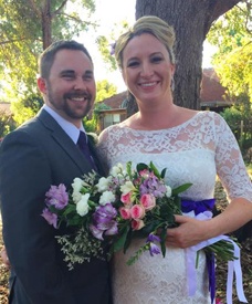 happy beautiful bride holding purple and white flowers with her handsome smiling groom