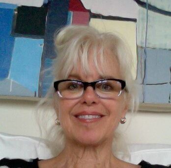A blonde woman wearing eyeglasses taking a selfie