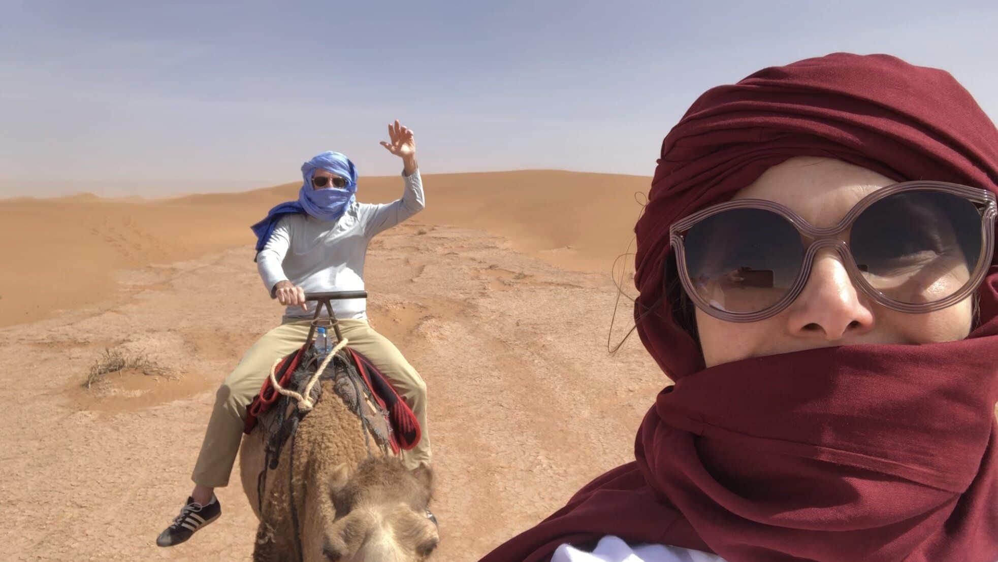 a couple in the desert riding camels